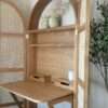 Foldable oak and rattan cabinet desk with brass handles, closed against a wall Aeshtetic craft