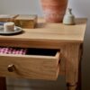 bedside table in natural pine wood with slim drawer, brass hardware, and bottom shelf