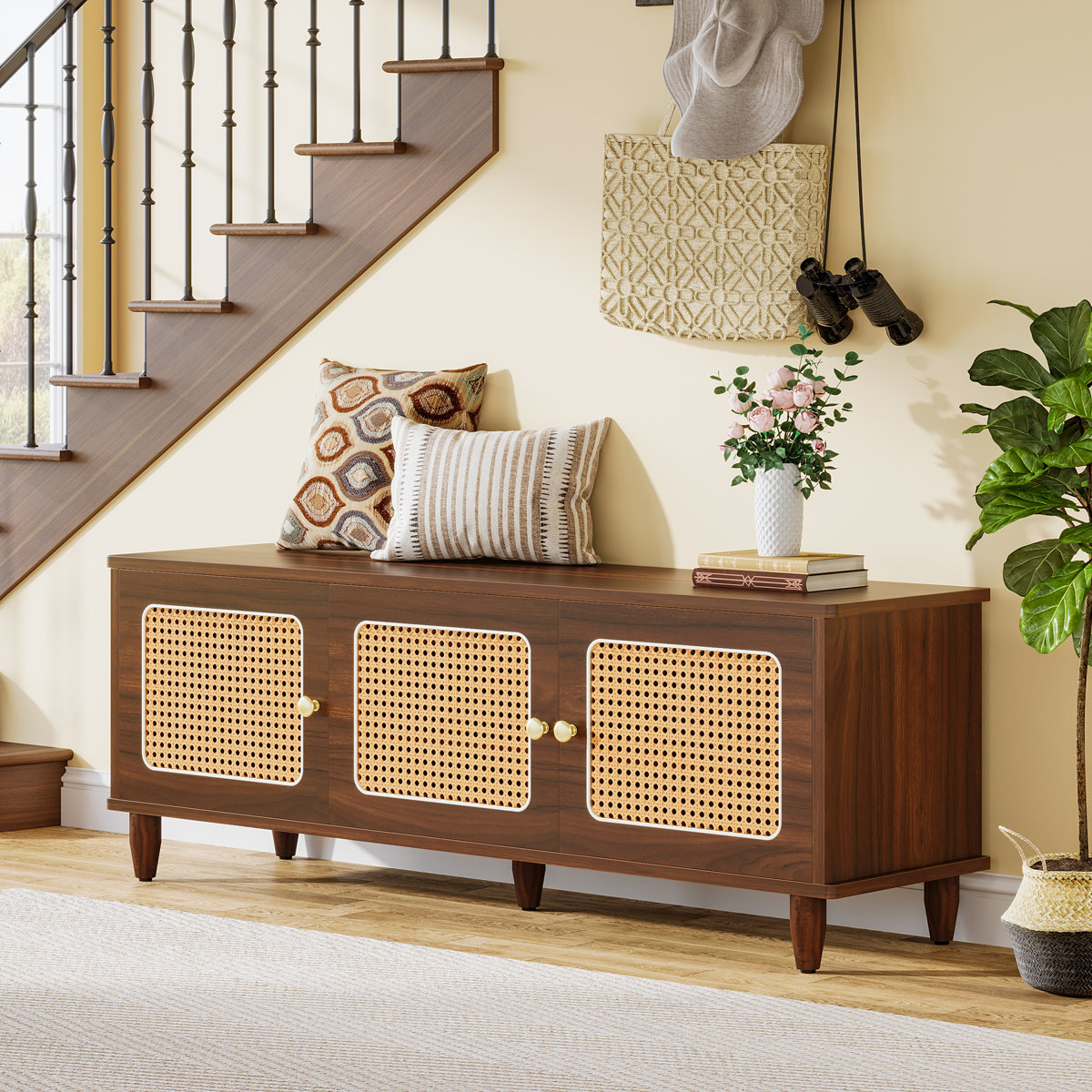 Walnut shoe storage bench with gold‑tone knobs and rattan door panels in a mid‑century modern style